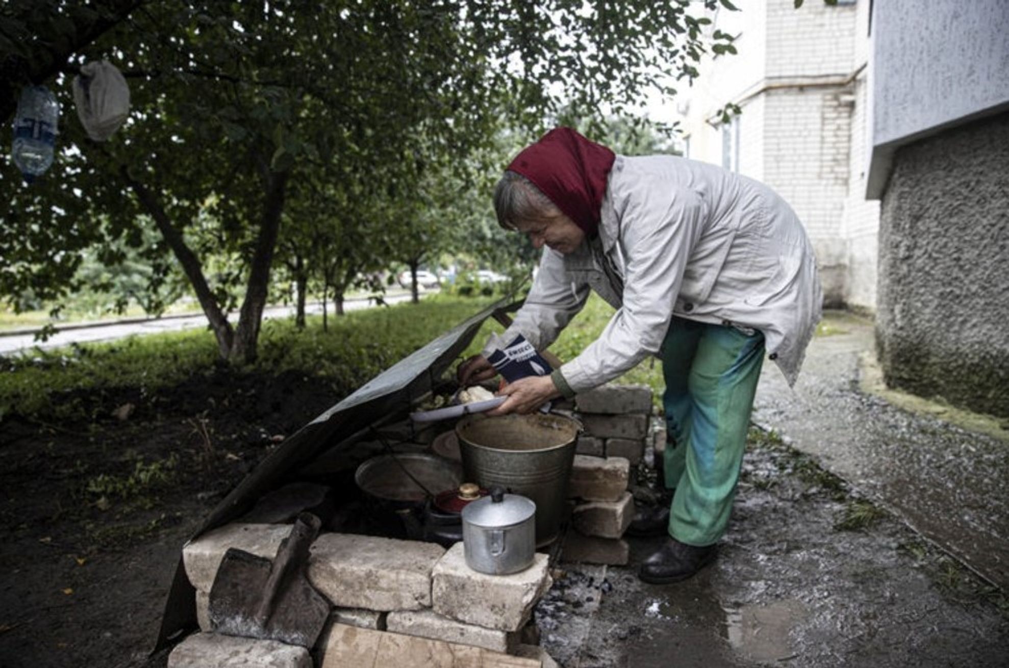 A woman in Kupiansk cooking food outside her apartment block