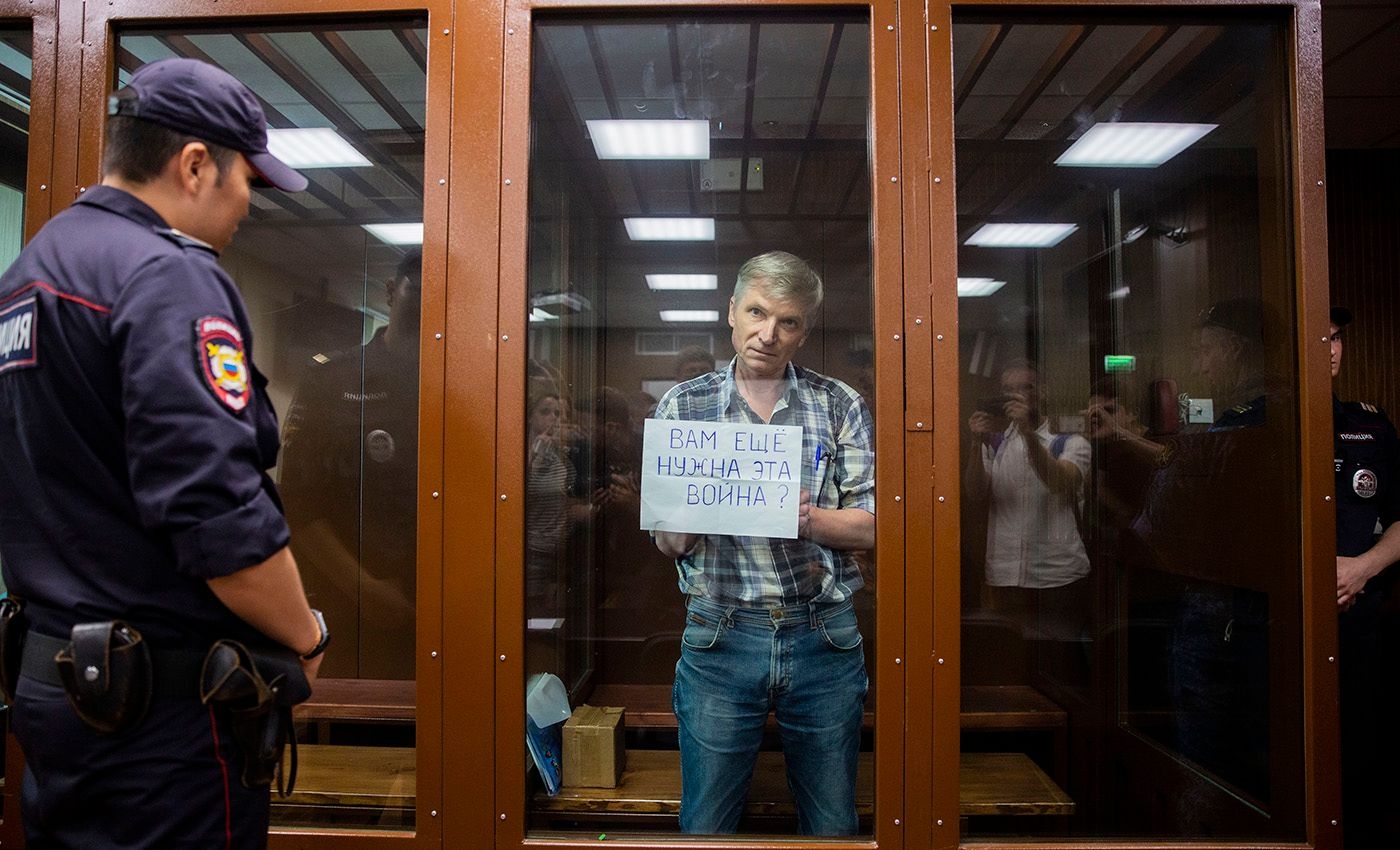 In June 2022, jailed Moscow city councillor Alexei Gorinov held up a sign reading “Do you still need this war?” from the courtroom’s glass cage ahead of his verdict. Photo: Alexandra Astakhova / Mediazona
