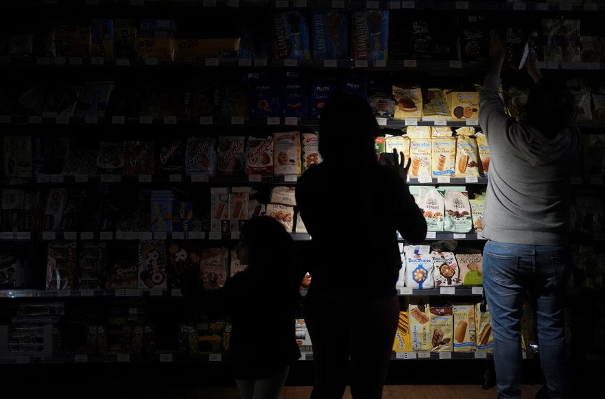 Shoppers use their phones and headlamps to navigate a supermarket during the mass blackout in Barcelona, Spain, on April 28, 2025. Photo: Bruna Casas / Reuters