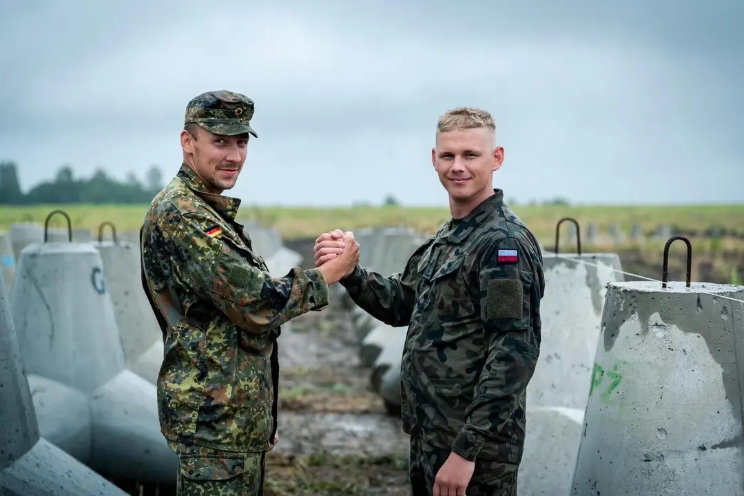 Polish and German soldiers pose for a picture in front of defensive fortifications on the Polish border. Photo: Bundeswehr Operational Command