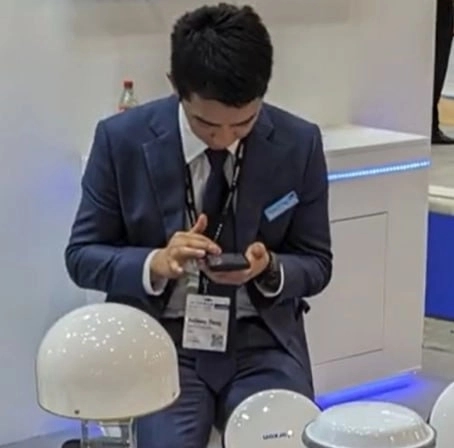Anthony Zheng, whose name is visible on his badge, looks at his phone at Harxon’s booth at the INTERGEO 2023 international trade fair