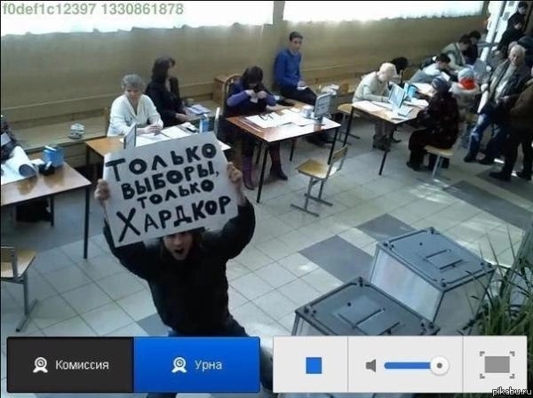 An activist at a polling station in Russia holding up a sign to a CCTV camera saying “Nothing but elections. Nothing but hardcore.”