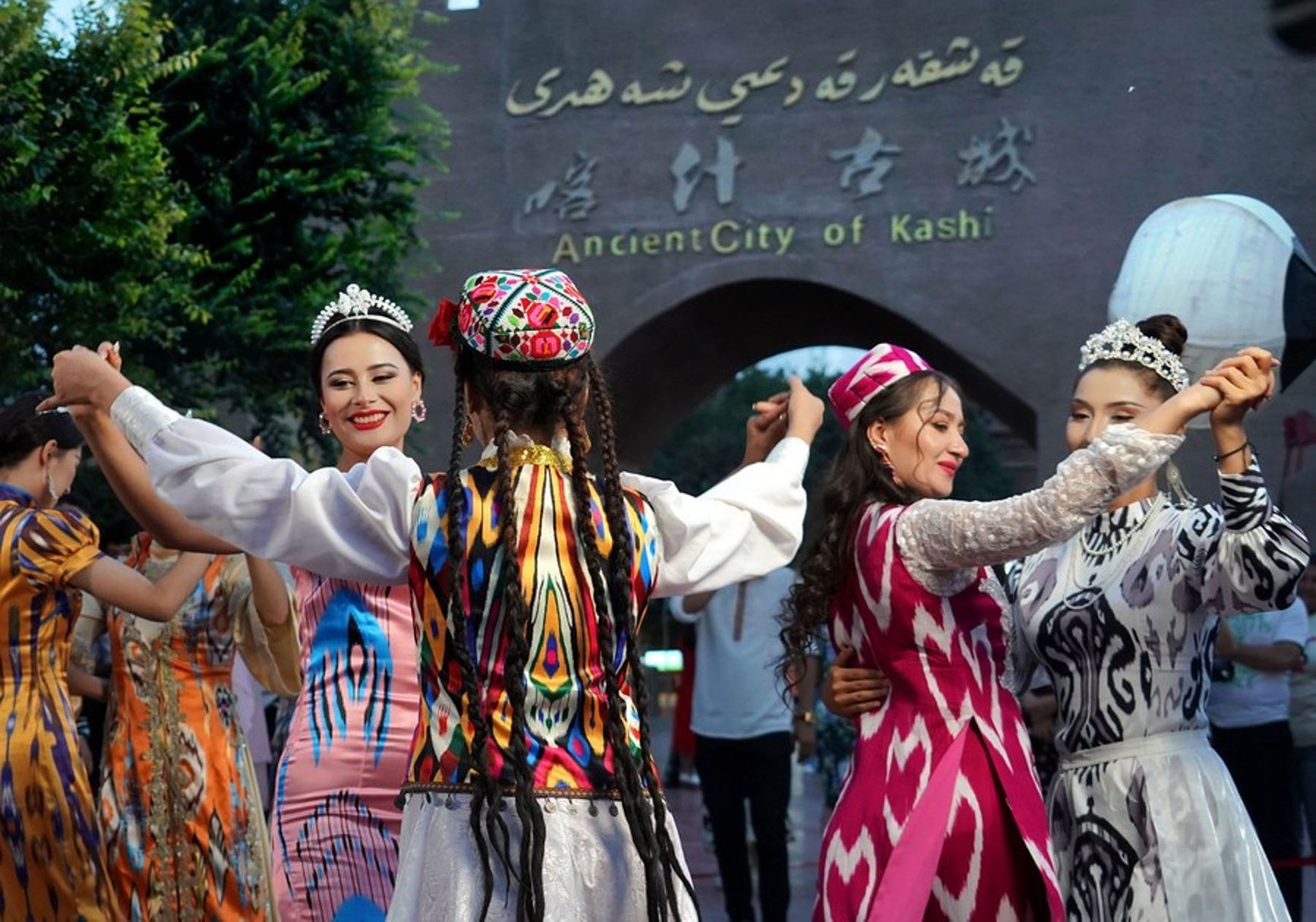 Dancers in front of the gates of the tourist zone of the ancient town of Kashgar in the Xinjiang Uyghur Autonomous Region in northwest China 