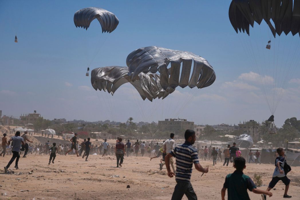 Palestinians chase parachuted aid in the city of Az-Zawaida, central part of the Gaza Strip – August 4, 2025 