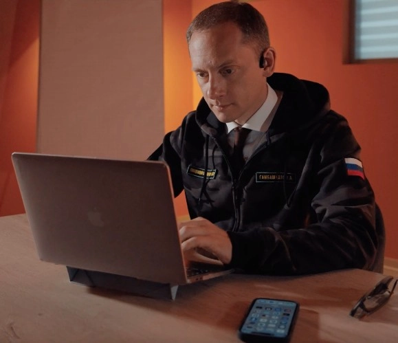 Ilya Gambashidze wearing a jacket with a patch reading “Russian Ideological Troops. Strength in Truth”